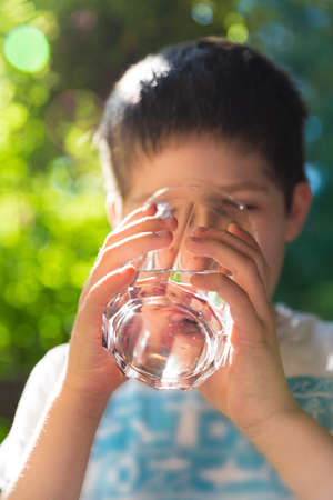 A boy drinking water on a hot summer dayの写真素材