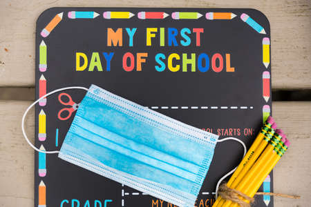 First day of school chalkboard with a face mask and school suppliesの写真素材