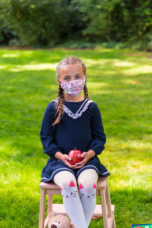 Schoolgirl holding a back to school sign and a face maskの写真素材
