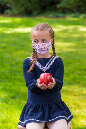 Schoolgirl holding a back to school sign and a face maskの写真素材