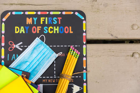 First day of school chalkboard with a face mask and school suppliesの写真素材