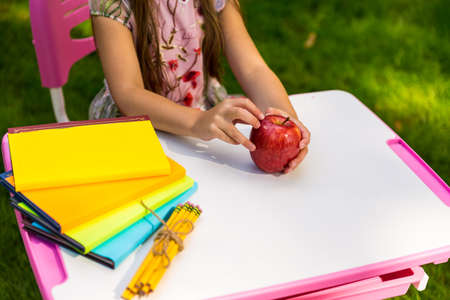 Schoolgirl holding red apple sitting at the deskの写真素材
