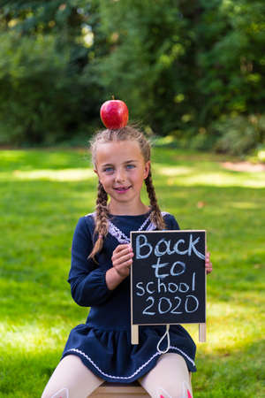 Schoolgirl holding a back to school sign and a face maskの写真素材