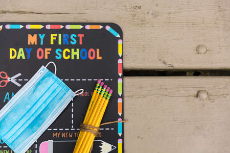 First day of school chalkboard with a face mask and school suppliesの写真素材