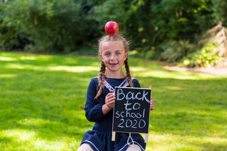 Schoolgirl holding a back to school sign and a face maskの写真素材