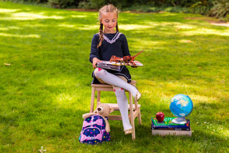 Schoolgirl sitting at the school desk outside in the parkの写真素材