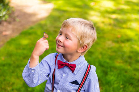 Happy blond boy holding a butterflyの写真素材