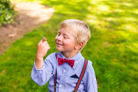 Happy blond boy holding a butterflyの写真素材
