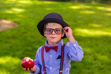 Happy boy with a hat holding a red appleの写真素材