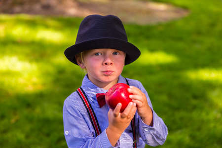 Happy boy with a hat holding a red appleの写真素材