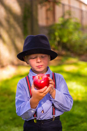 Happy boy with a hat holding a red appleの写真素材
