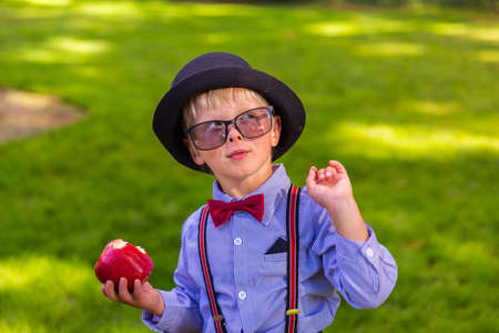 Happy boy with a hat holding a red appleの写真素材