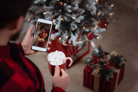 A couple enjoys hot cocoa over the video call during coronavirus quarantinの写真素材