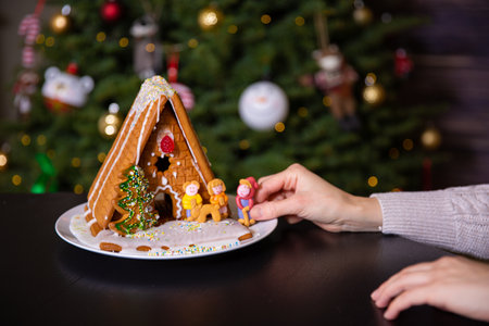 A boy decorating Christmas gingerbread house  at homeの写真素材