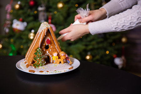 A boy decorating Christmas gingerbread house  at homeの写真素材