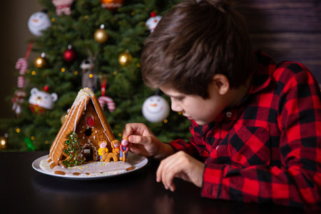 A boy decorating Christmas gingerbread house  at homeの写真素材