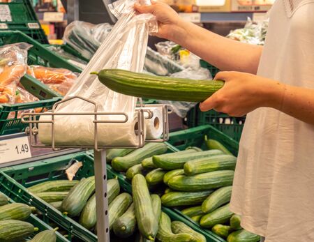 Customer puts cucumber in plastic bagの写真素材