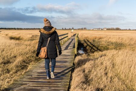 Woman running in winter on the beach path at the North Sea