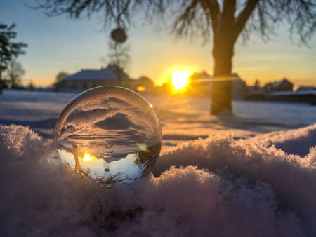 Snow globe in a winter landscape at sunsetの写真素材