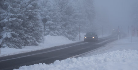 Car on a winter road with fog and snowの写真素材