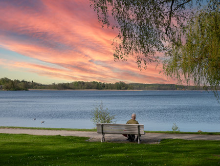 Sunset on a lake in the Mecklenburg Lake District with an old man on a benchの写真素材