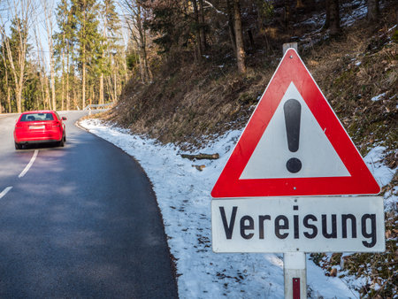 Red warning sign about icing of the road in winter in Germanの写真素材