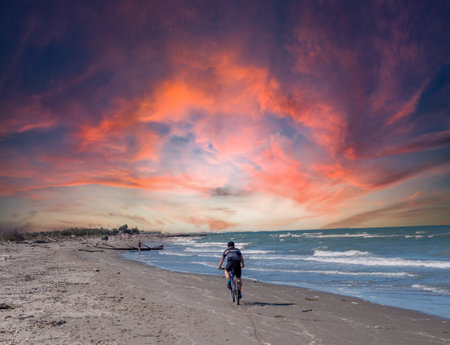 man rides a bicycle on the beach at sunsetの写真素材