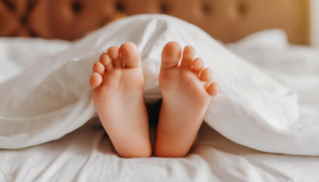 Child's legs are covered with white bed linenの素材