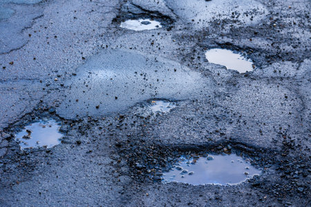 Potholes on the road after frost in winter in springの写真素材