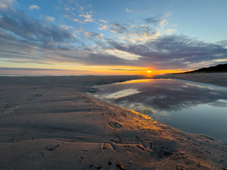 Sunrise over the Polish Baltic Sea in the morning with reflection of the clouds on a sandbankの写真素材
