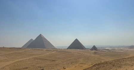 Pyramids of Giza with blue sky and desert in the foreground