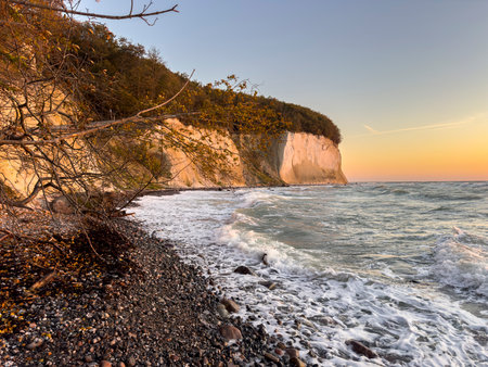 Chalk cliffs on RÃ¼gen are illuminated by the sun with a stone beach in the foreground autumn imageの写真素材