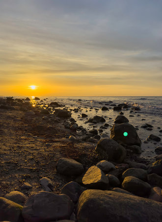Sunset on the beach with large rocks in the water on the Baltic Sea on Ruegen, verticalの写真素材