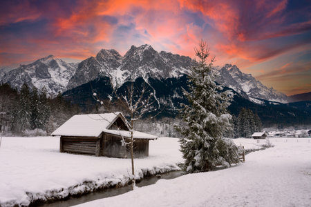 Old wooden house at the foot of the Zugspitze in the Alps at sunsetの写真素材