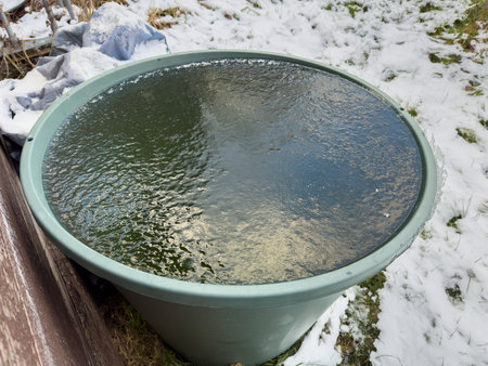 Rain barrel in the garden is frozen over in the cold in winterの写真素材