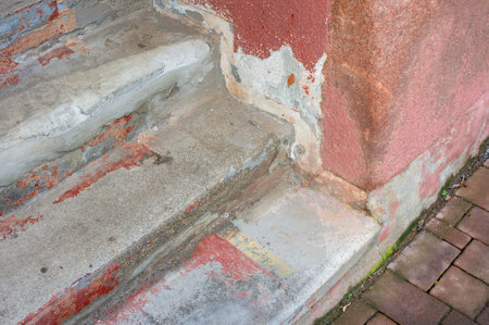 Structural damage to a staircase at the entrance to the house with peeling plaster on the wall