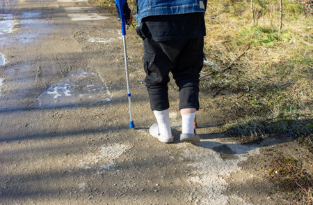 Old man with walking aid in winter on black ice, risk of slipping