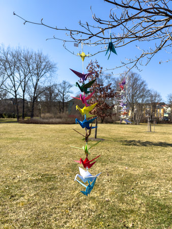 Origami paper cranes in bright colors flying in the wind on a tree verticallyの写真素材