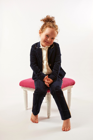 Little girl in black suit sitting and smilingの写真素材