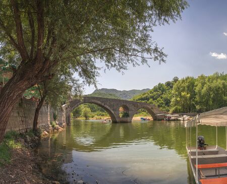 Skadar lake, Montenegro - 07.15.2018.  Panoramic view of the Old Bridge over Crnojevica river, Rijeka Crnojevica, and the tourist area near the bridge, Rijeka Crnojevica.のeditorial素材