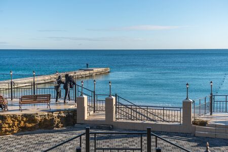 Odessa, Ukraine - 12.27.2018. Lonely people on the pier by the sea on a sunny winter day