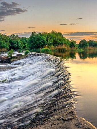 Beautiful view of the dam on the Southern Bug River at sunset. Village of Migiya, Ukraine, on a...