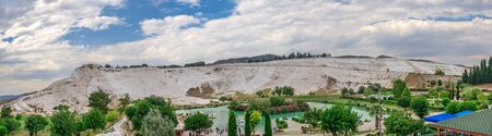 Pamukkale, Turkey â 07.14.2019. White mountain and green lake in Pamukkale. Panoramic view from the side of the village on a cloudy summer evening.のeditorial素材