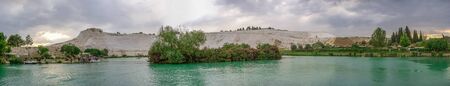 Pamukkale, Turkey â 07.14.2019. White mountain and green lake in Pamukkale. Panoramic view from the side of the village on a cloudy summer evening.のeditorial素材