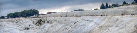 Pamukkale, Turkey â 07.14.2019. Many tourists on Pamukkale white Mountain. Panoramic view from the side of the village on a cloudy summer evening.のeditorial素材