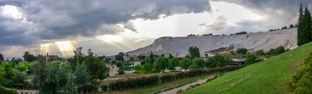 Pamukkale, Turkey â 07.14.2019. White mountain and green lake in Pamukkale. Panoramic view from the side of the village on a cloudy summer evening.のeditorial素材