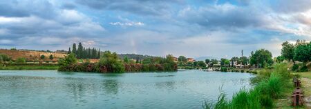 Pamukkale, Turkey â 07.14.2019. White mountain and green lake in Pamukkale. Panoramic view from the side of the village on a cloudy summer evening.のeditorial素材