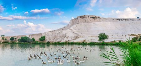 Pamukkale, Turkey â 07.15.2019. White mountain and green lake in Pamukkale. Panoramic view from the side of the village on a summer morningの写真素材