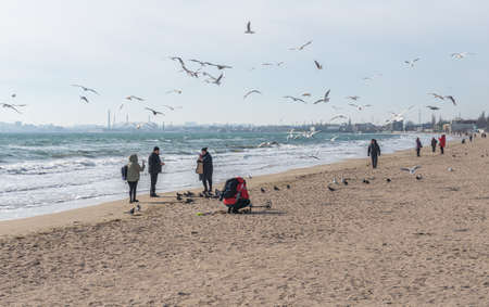 Odessa, Ukraine 07.02.2022. A man look for valuables using metal detector on the Luzanivka beach in Odessa, Ukraine, on a sunny winter dayのeditorial素材