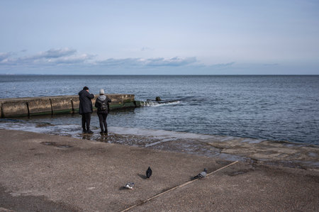 Odessa, Ukraine 19.02.2023. People walk by the sea on a cloudy winter day on Lanzheron beach in Odessa, Ukraineのeditorial素材